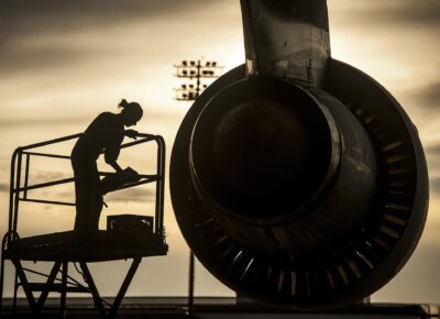 Flygtekniker inspekterar en jetmotor i motljus